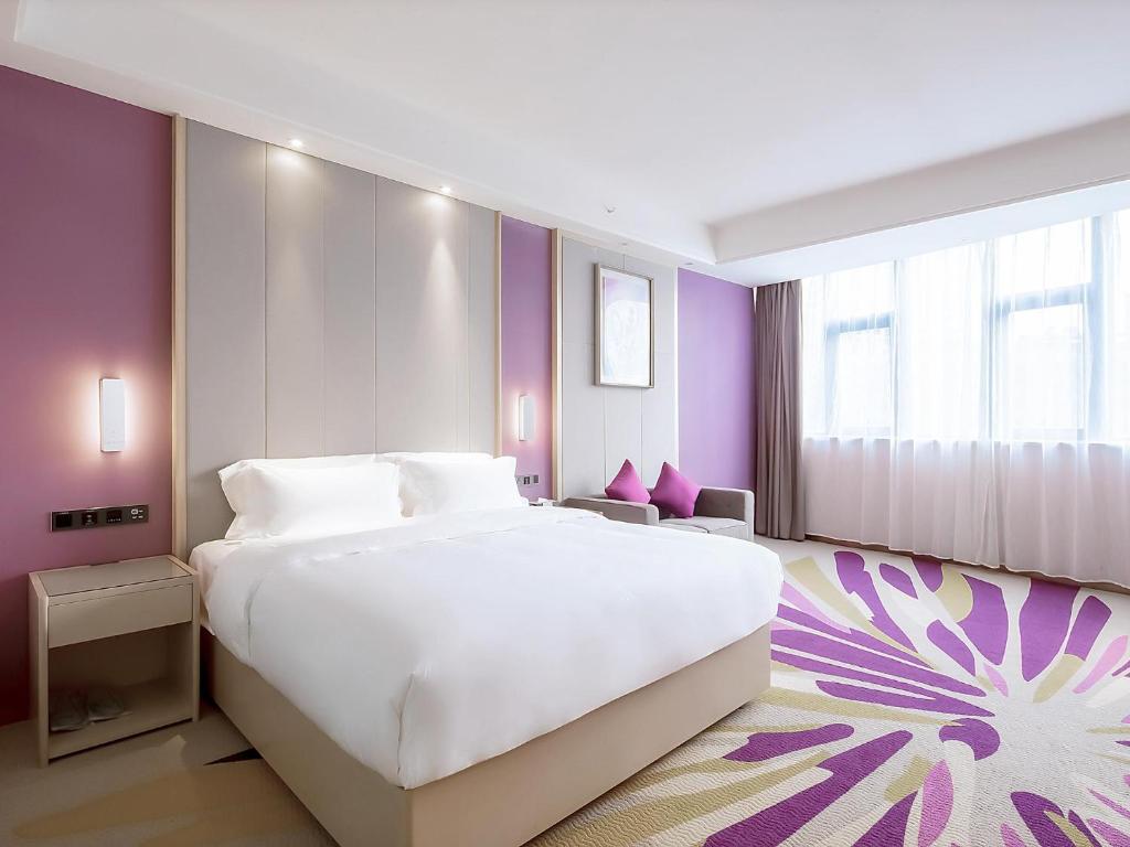 星沙Lavande Hotel Changsha Xingsha Center的卧室配有一张白色大床和紫色墙壁
