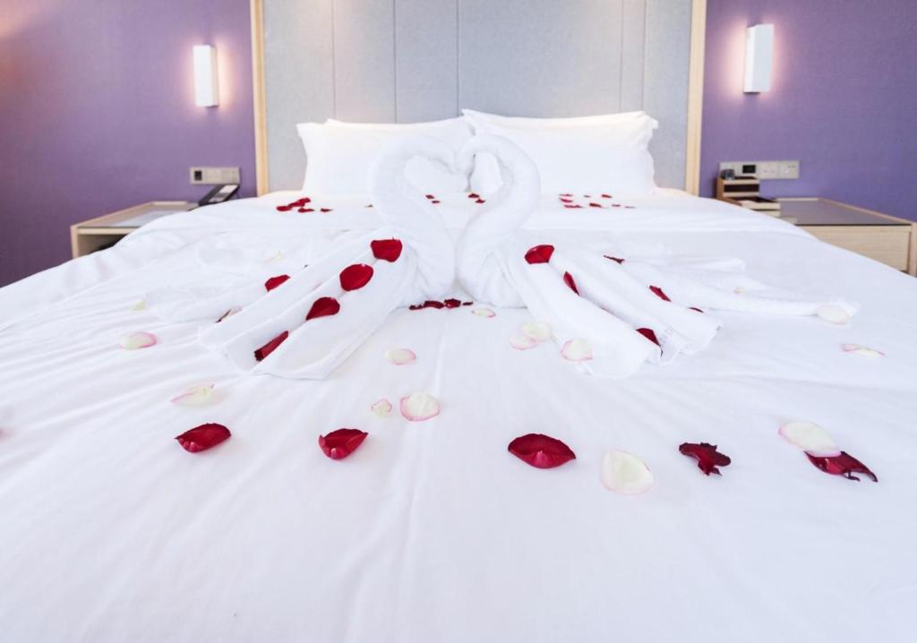 日照Lavande Hotel Rizhao Xinshi District Branch的床上有玫瑰和手套
