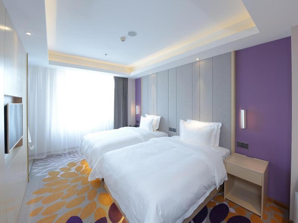 长春Lavande Hotel Changchun Hangkong University Fanrong Road Metro Station的紫色墙壁的酒店客房内的两张床