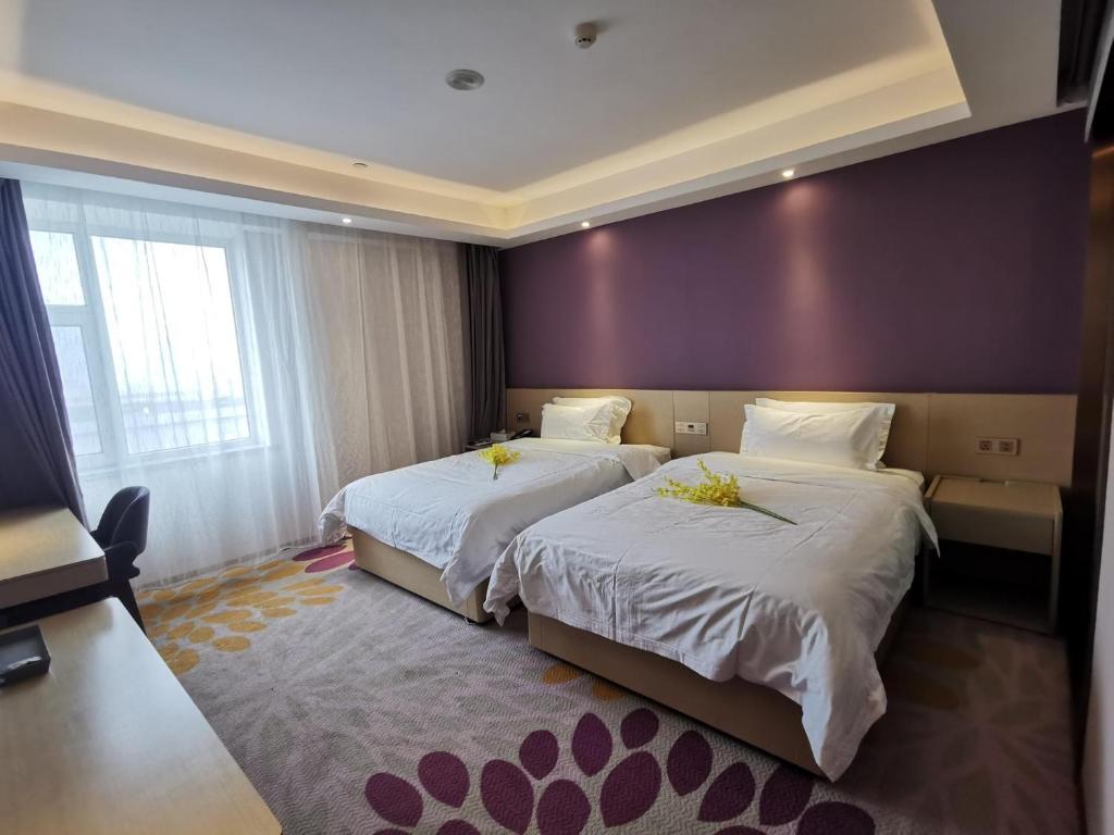 长春Lavande Hotel (Changchun Yiqi Branch)的酒店客房设有两张床和紫色墙壁。
