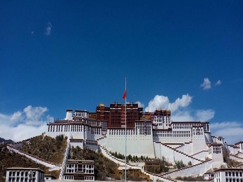 拉萨Lavande Hotel (Lhasa City Government Xizang University Branch)的一座白色的大建筑,上面有红旗