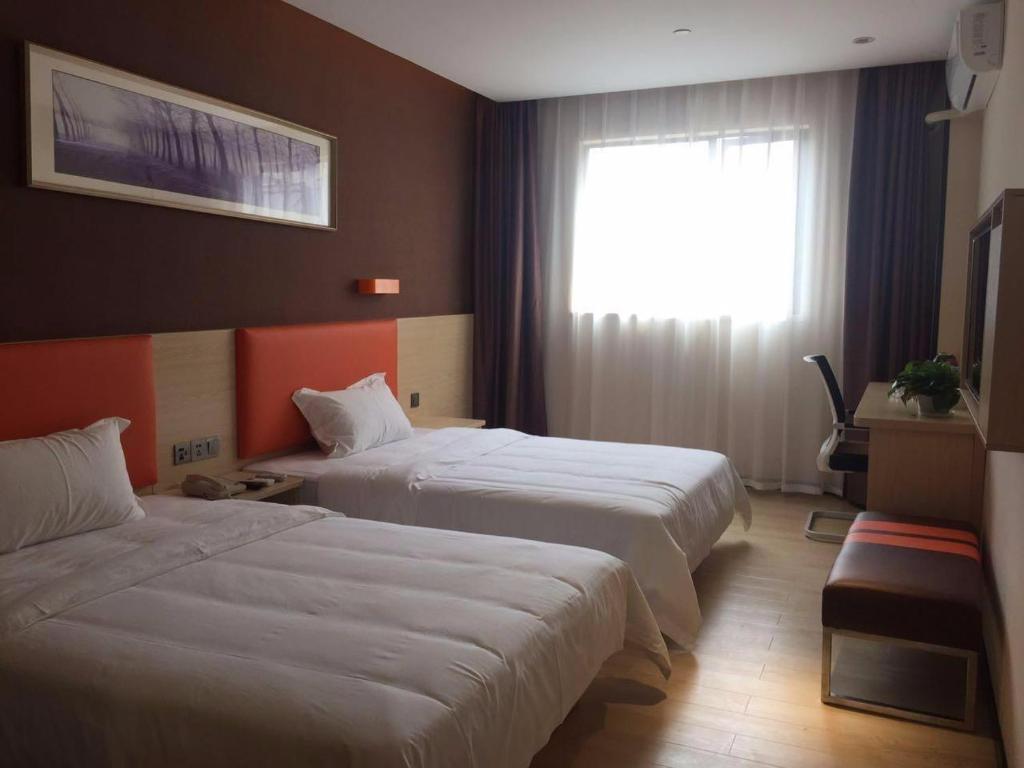 焦作7 Days Premium Jiaozuo Renmin Road Teachers College的酒店客房设有两张床和窗户。