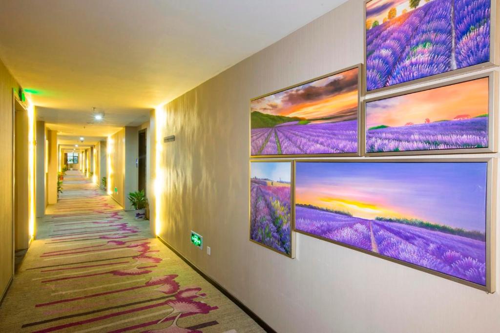 南昌Lavande Hotel Nanchang West Railway Station Xinjian Branch的墙上有几幅画作的走廊