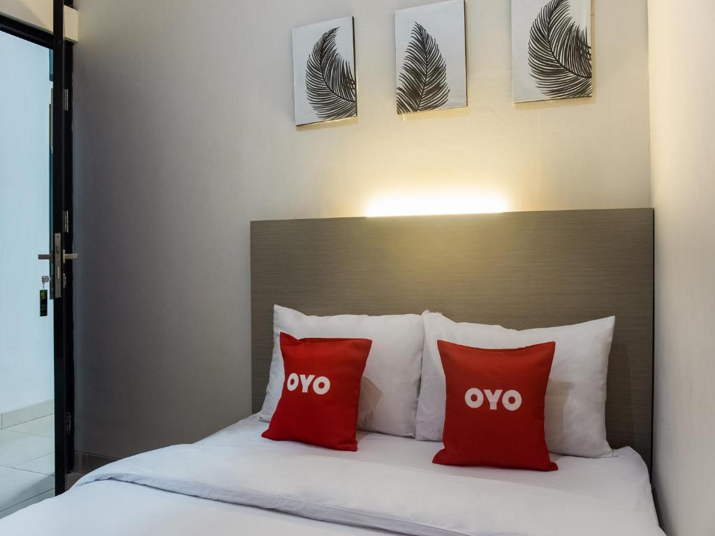TelukjambeOYO Life 3251 D'daun Inn的配有红色枕头的床的酒店客房