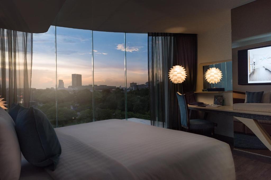 曼谷The Xtreme Suites的一间卧室配有一张床、一张书桌和一个窗户。