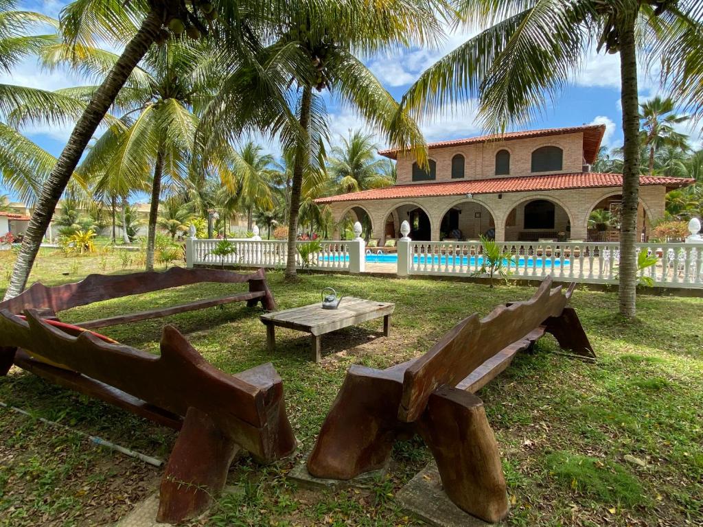 圣米格尔-杜斯米拉格里斯AQUALUNA POUSADA的一个带长椅的公园和一座棕榈树建筑