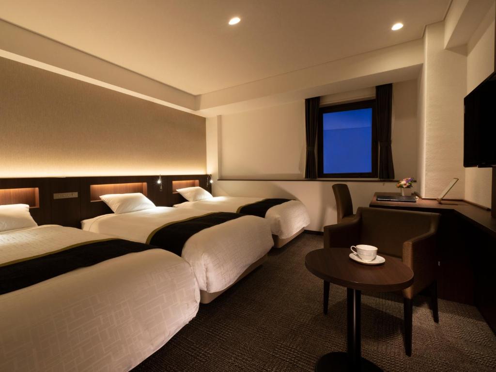 名古屋公主花园酒店的酒店客房设有四张床和一张桌子。