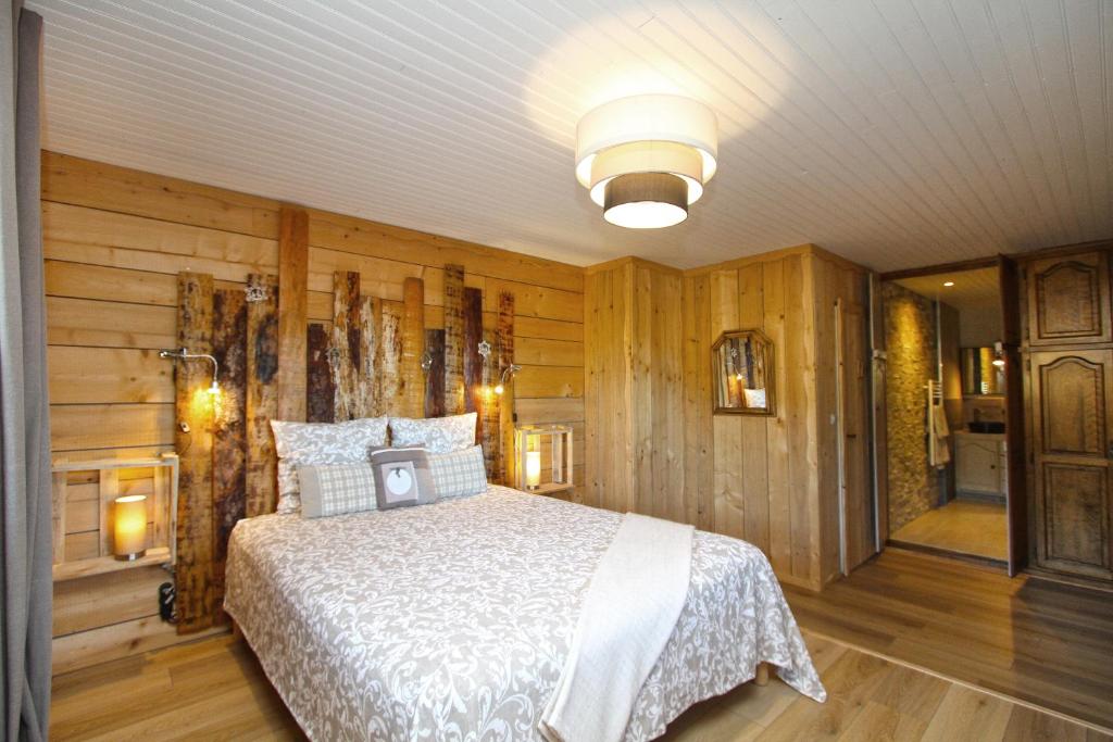莱瓦尔坦Au Domaine de PY的卧室配有一张床铺,位于带木墙的房间内
