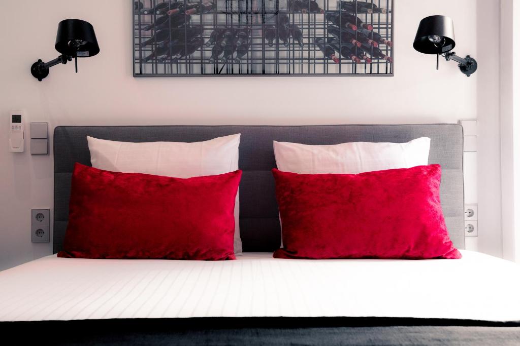 乌得勒支ZIES精品酒店的一张带两个红色枕头和黑色床头板的床