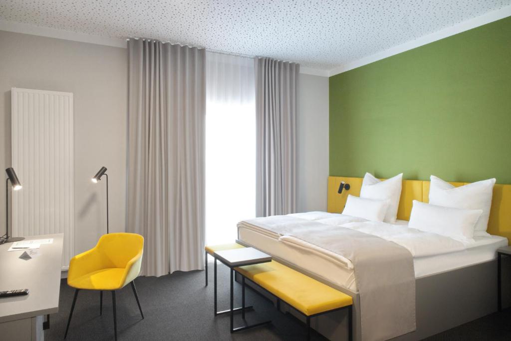 明斯特Hotel Adler Münster的酒店客房,配有床和黄色椅子