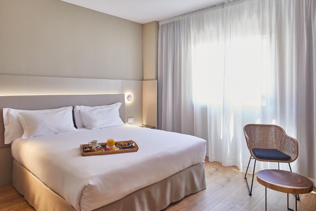 萨拉戈萨阿拉贡斯肯瑞诺酒店的一间酒店客房,配有一张床铺,上面放着一个食物托盘