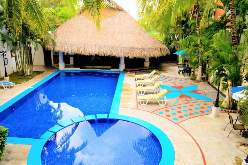 曼萨尼约布拉瓦海岸酒店 的一个带草伞和椅子的游泳池