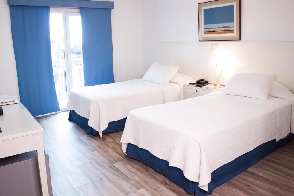 亚松森Hotel Cecilia的酒店客房设有两张床和窗户。
