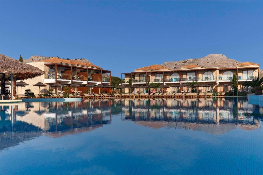 科林比亚Atlantica Holiday Village Rhodes的一个带椅子和建筑的大型游泳池的度假酒店