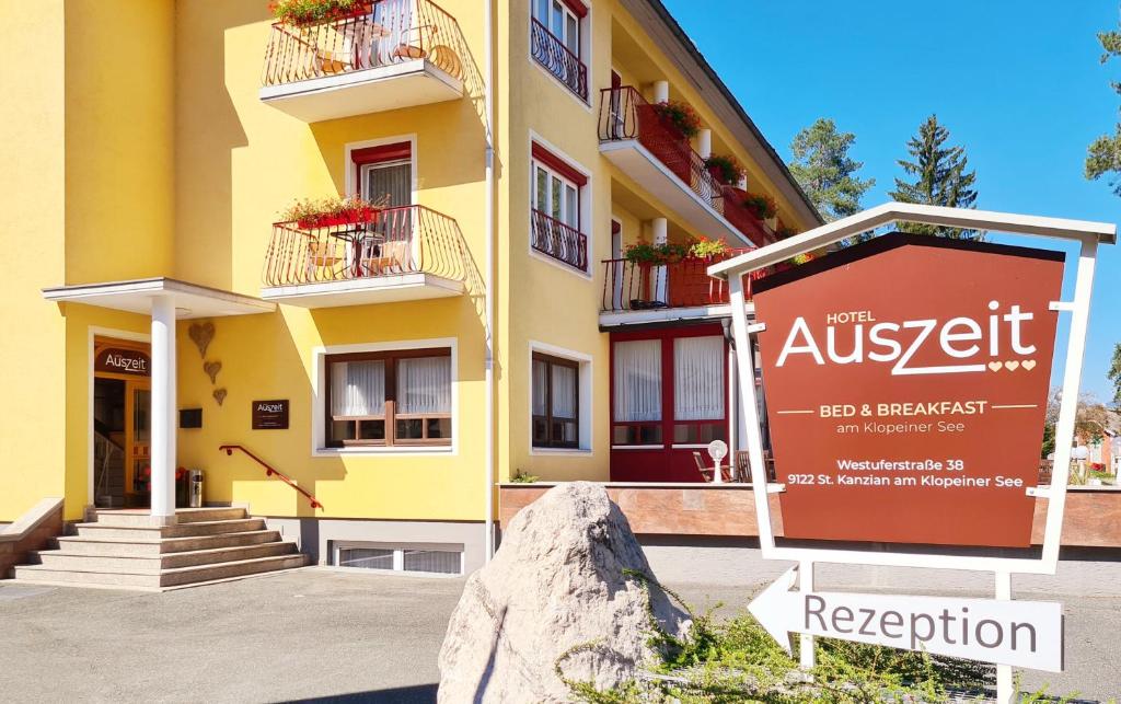圣卡尼兹Hotel Auszeit的黄色的建筑,前面有标志