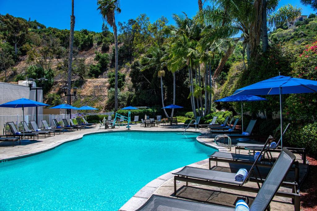 圣地亚哥Sheraton Mission Valley San Diego Hotel的一个带椅子和遮阳伞的游泳池