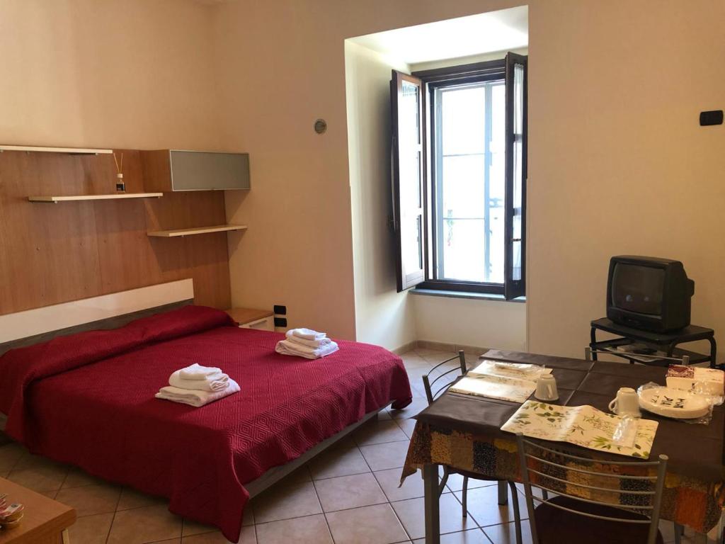 卡坦扎罗Monolocale in Via Poerio的一间卧室配有红色的床、一张桌子和一台电视