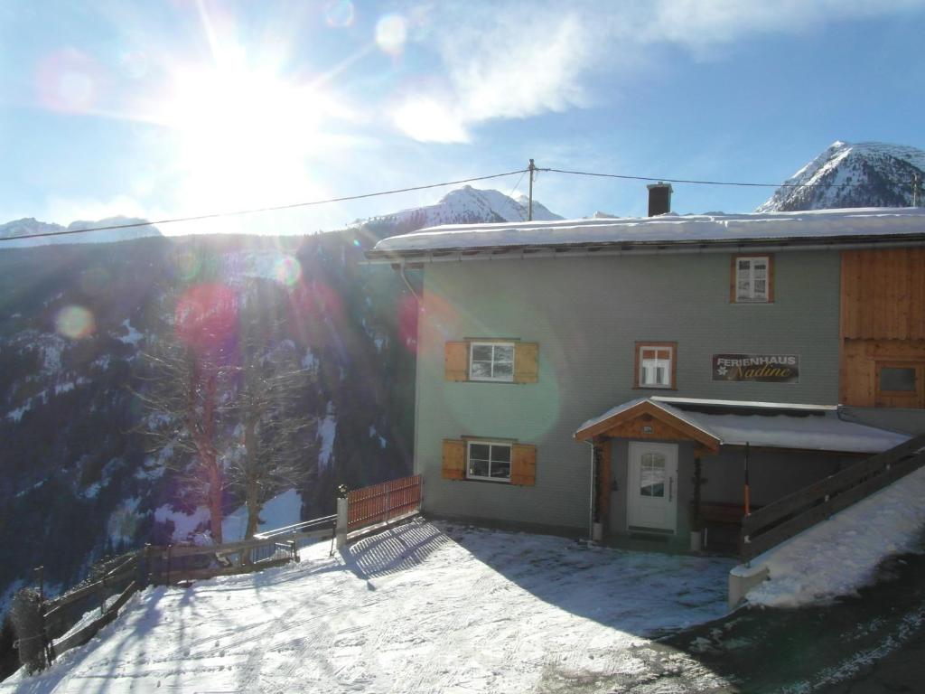 卡普尔Ferienhaus Nadine的山旁的一座积雪的建筑