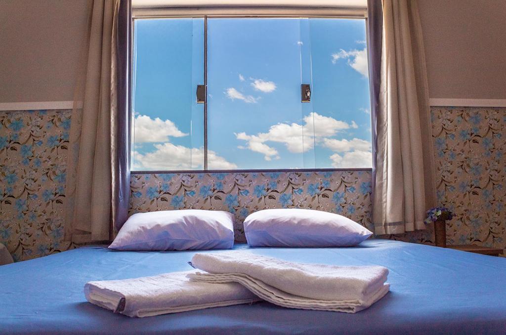 圣若昂-巴蒂斯塔-杜格罗里亚Pouso Oliveira Suítes的一张带两条毛巾的床和窗户