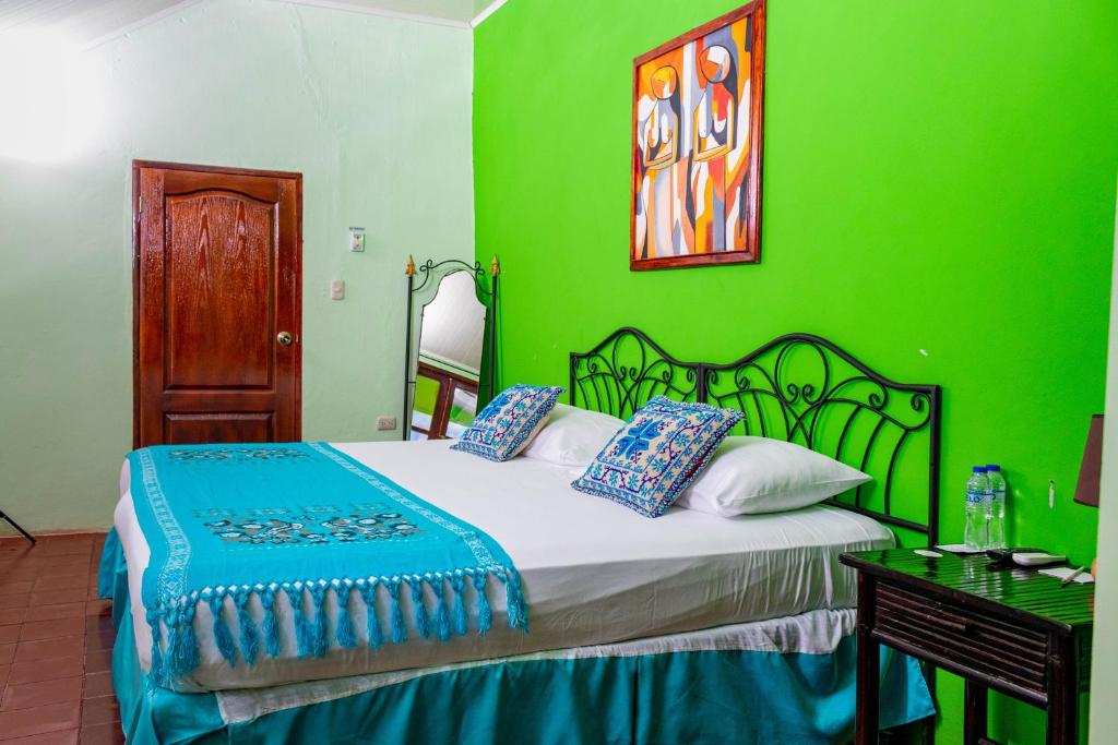 SomotoRual's Hotel的绿色卧室,配有床和绿色的墙壁