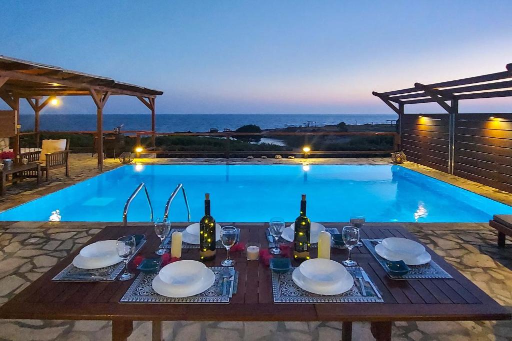 里科索翁CRYSTAL VILLAS的游泳池旁配有带葡萄酒瓶和玻璃杯的餐桌