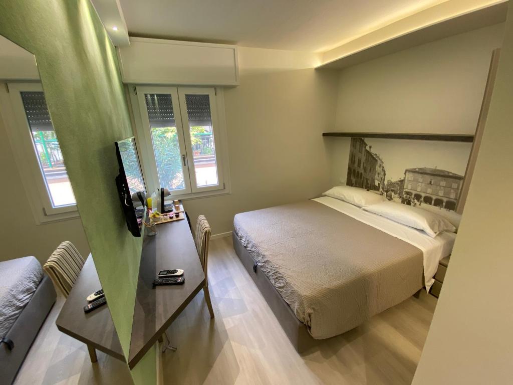 卡普里Affittacamere Ventisettembre的一间卧室配有一张床、一张桌子和两个窗户