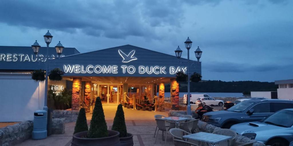 巴洛赫Duck Bay Hotel & Restaurant的一座建筑,上面有标志,上面写着欢迎客人去鸭湾