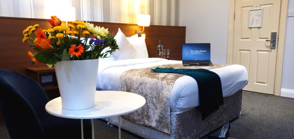 都柏林The Gate Hotel的一间卧室配有一张带花瓶的床和一台笔记本电脑