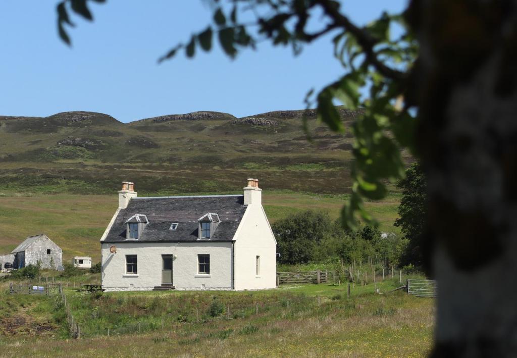 邓韦根Dunvegan Castle The Farmhouse Cottage的田间中的一个白色的旧房子