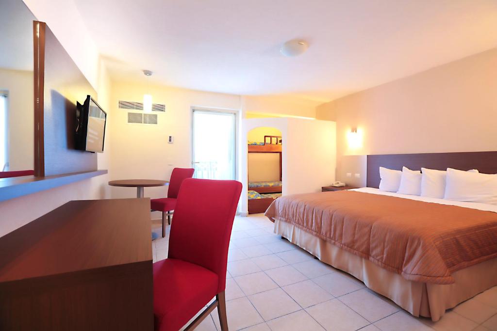 巴亚尔塔港Crown Paradise Club All Inclusive的酒店客房,配有一张床和一张红色椅子