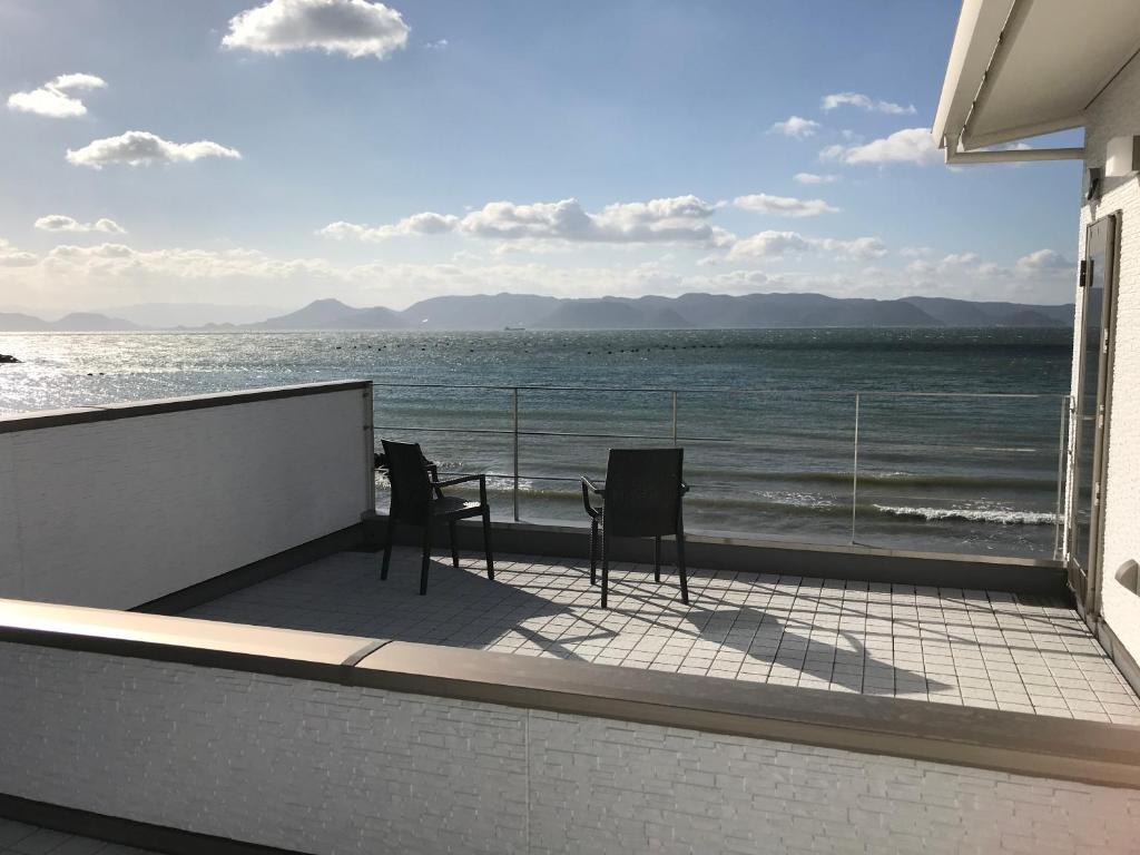 直岛町UOGASHI 7070 Ocean View的俯瞰大海的阳台配有两把椅子和一张桌子