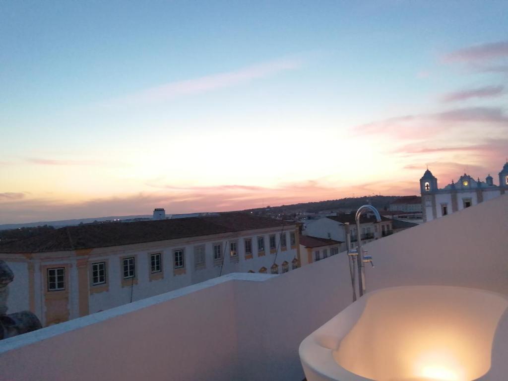埃武拉Evora Inn的一座享有日落美景的建筑屋顶上的浴缸