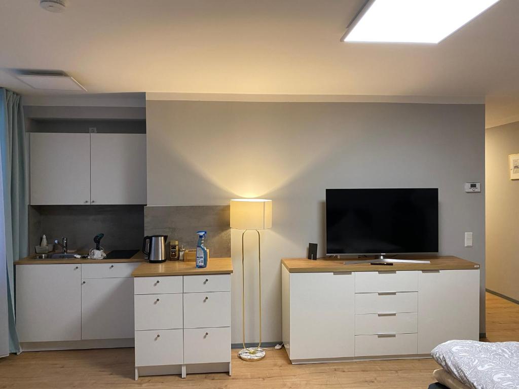 纽伦堡City Studio-Apartment am Hauptbahnhof N6的厨房配有白色橱柜和平面电视。