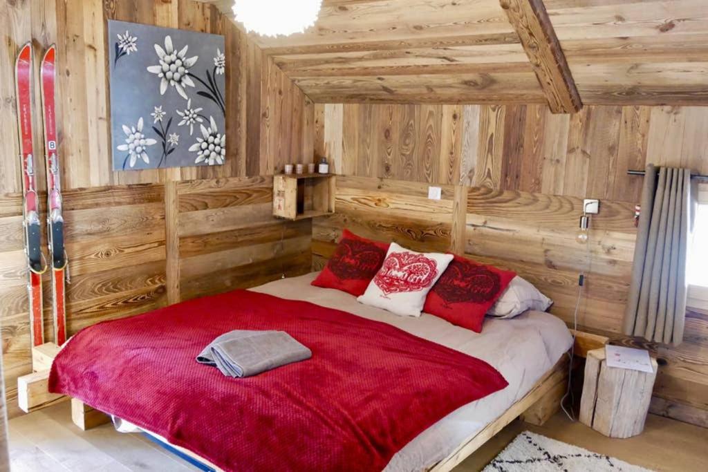 拉克吕萨chalet coup de coeur+véhicule 4*4 ; 9 places à dispo的一间卧室设有一张红色大床和木墙