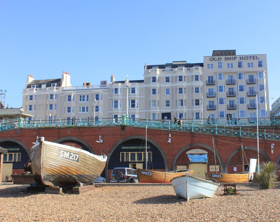 布莱顿霍夫The Old Ship Hotel的坐在大楼前的海滩上的三艘船
