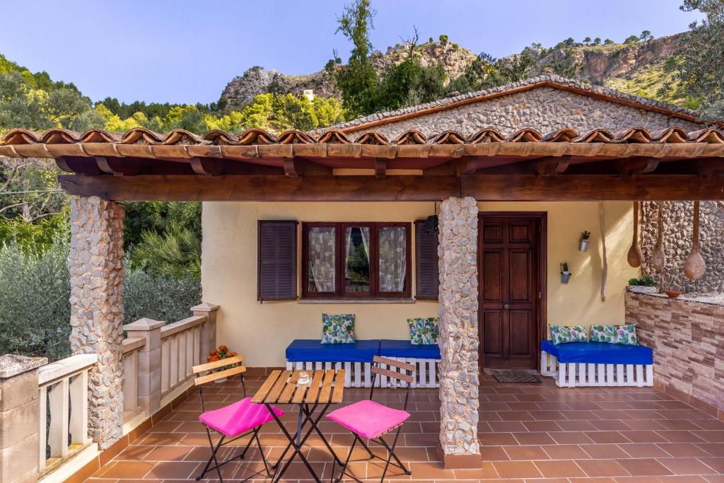 Cala TuentCan Sito的一个带粉色和蓝色椅子的庭院和一座房子