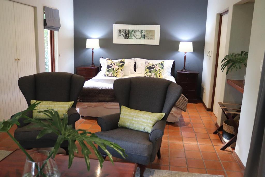 白河Heuglins Lodge的一间卧室配有两把椅子、一张床和一张桌子