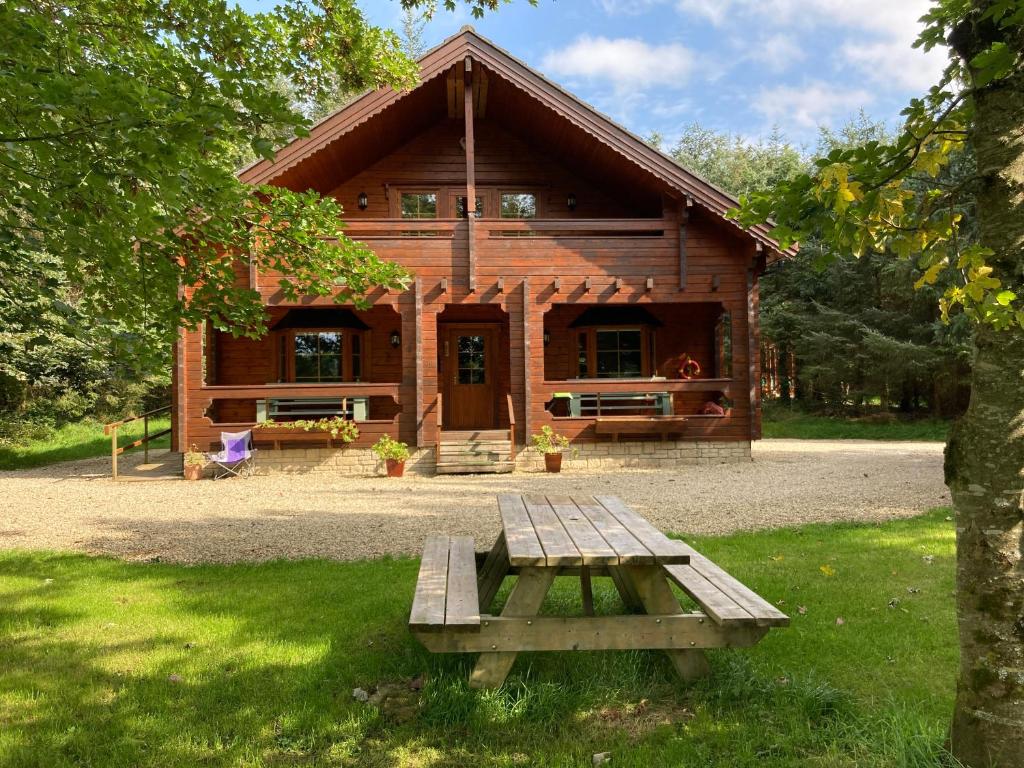 百利科内尔Riverside log cabin的小木屋前方设有野餐桌