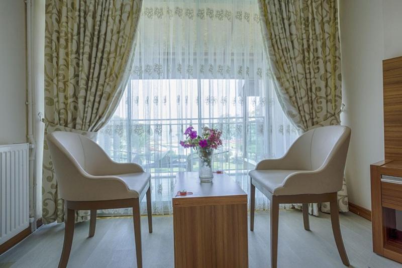 库古库俞RA Resort Otel的一间设有两把椅子、一张桌子和一个窗户的房间