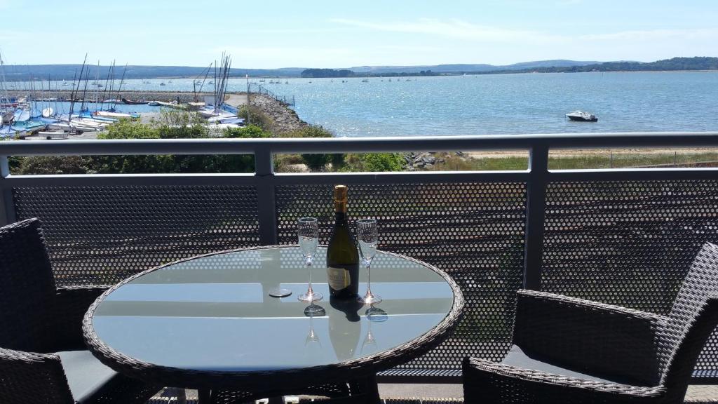 浦耳Beach Point的阳台上的玻璃桌和一瓶葡萄酒