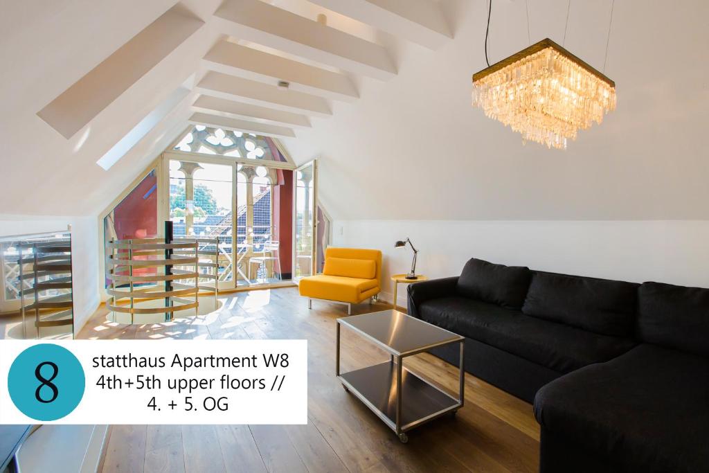 科隆statthaus - statt hotel的客厅配有黑色沙发和黄色椅子