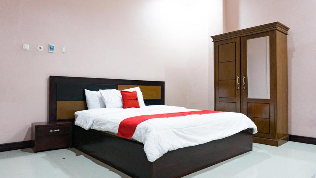 蒂米卡RedDoorz @ Jalan Cendrawasih Timika的一间卧室配有一张大床和一个木制橱柜