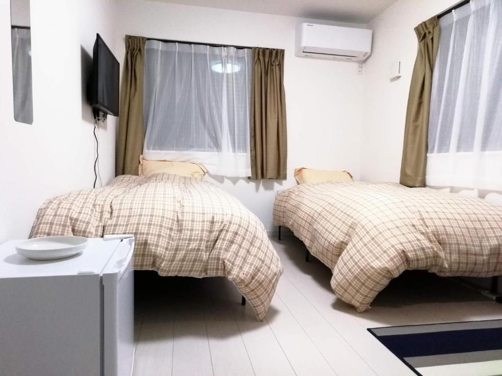 川崎クレアゲハウス新百合ケ丘的一间带两张床的卧室和一台电视
