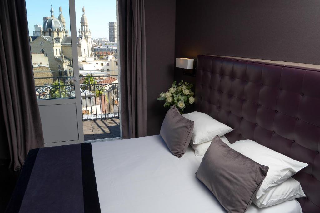巴黎圣查尔斯酒店的一间卧室设有一张大床和大窗户
