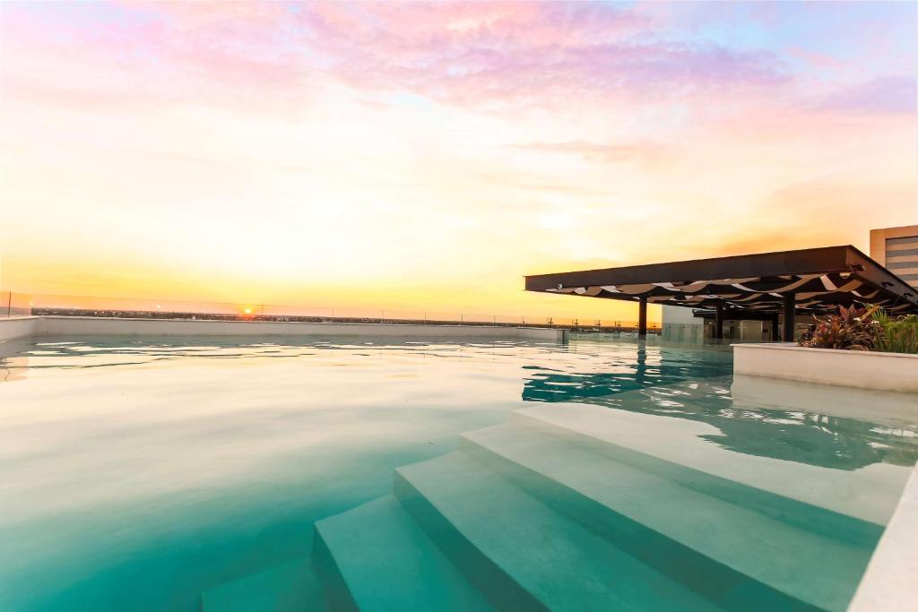 梅里达NH Collection Merida Paseo Montejo的一座享有日落美景的游泳池