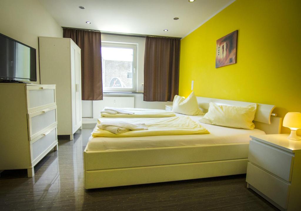 伍珀塔尔斑尾林鸽酒店 - 如家住宿的一间卧室设有两张床和黄色的墙壁