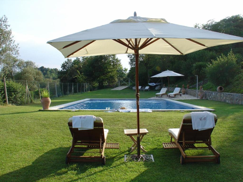 Sales del Llierca坎塞罗拉酒店的游泳池旁的两把椅子和一把遮阳伞