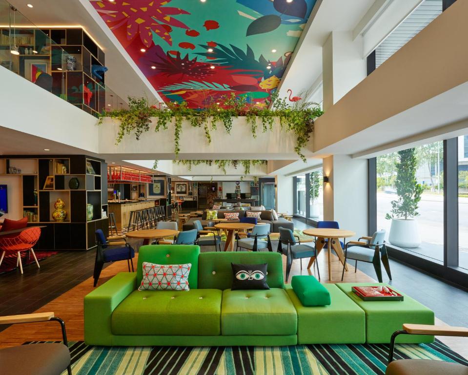 吉隆坡citizenM Kuala Lumpur Bukit Bintang的一个带绿色沙发和桌椅的图书馆