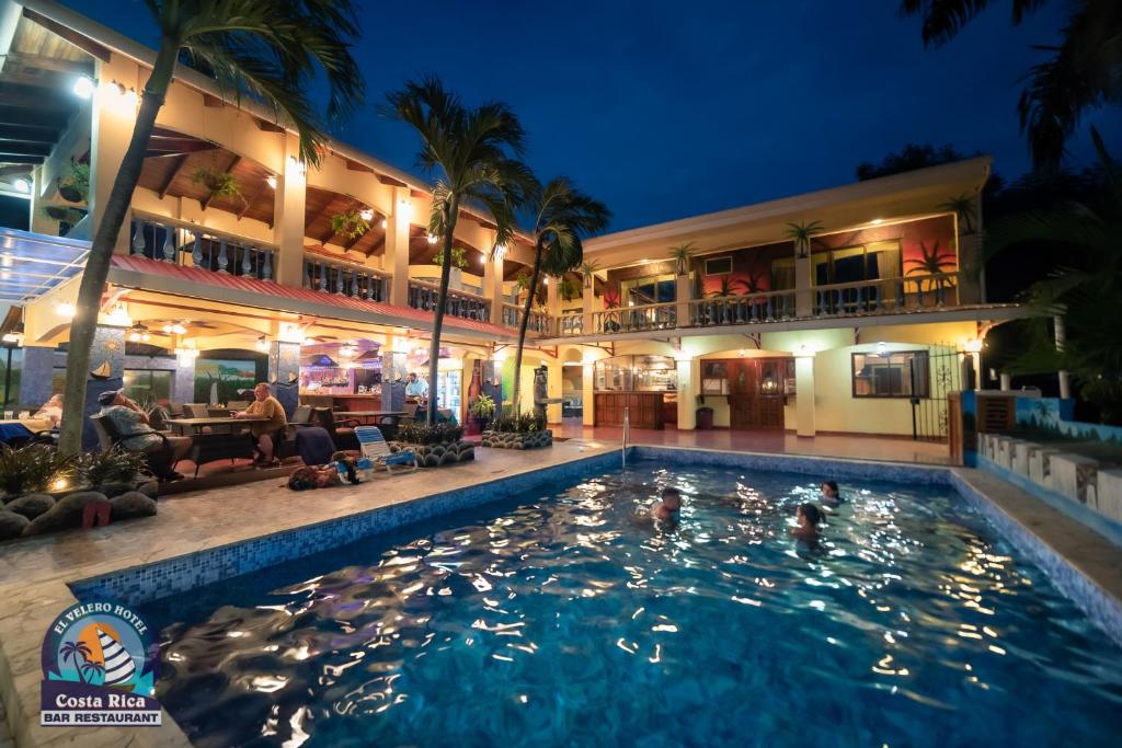 普拉亚埃尔莫萨Hotel El Velero的晚上在酒店前面的一个游泳池