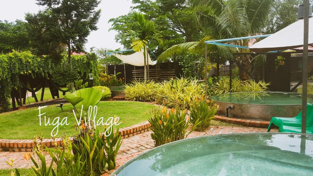 马六甲Fuga Village BeachGetaway的花园内的游泳池,配有桌椅